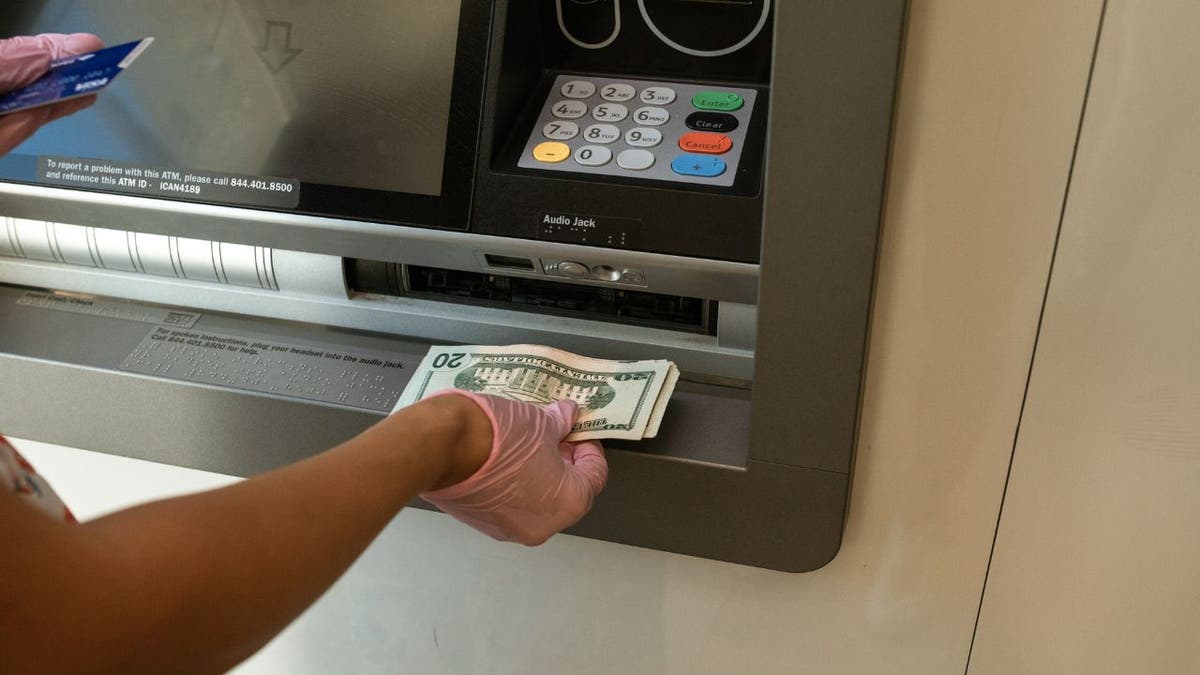 Frau nimmt Bargeld aus einem Geldautomaten.