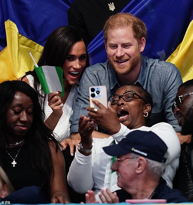 The couple laughed as Meghan waved a Nigerian flag and took selfies with others within the crowd