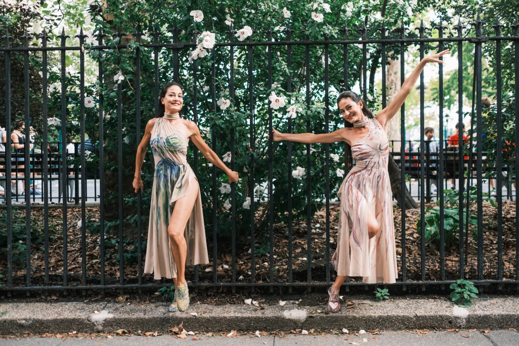Die Zwillinge Gabriela Mordocea und Mihaela Mordocea tanzen im John Jay Park vor einem schwarzen Zaun als Hintergrund. 