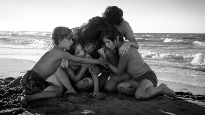 Eine Gruppe von Kindern und zwei Frauen, die sich am Strand umarmen, im Film „Roma“.