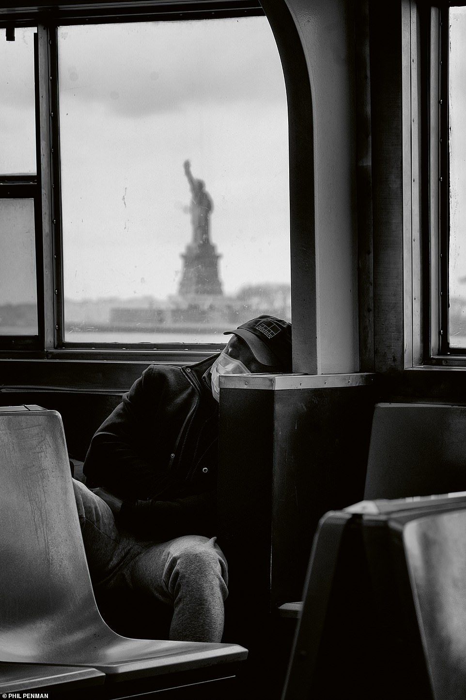 Die Freiheitsstatue wacht während des Coronavirus-Ausbruchs im März 2020 über einen Mann, der auf der Staten Island Ferry schläft