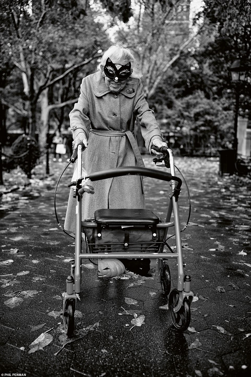 Eine ältere Frau mit einer Verkleidungsmaske bleibt in der Halloween-Nacht im Washington Square Park im Oktober 2019 stehen, um für ein Foto zu posieren