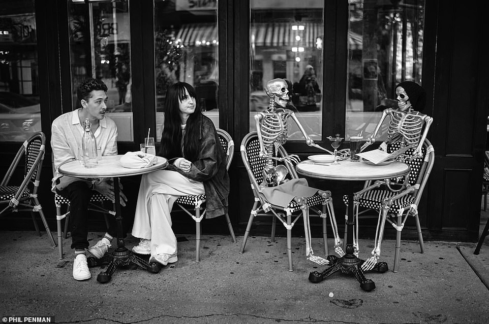 Ein Paar wurde gesehen, wie es an Halloween 2022 neben zwei Skeletten vor einem Restaurant in Soho saß
