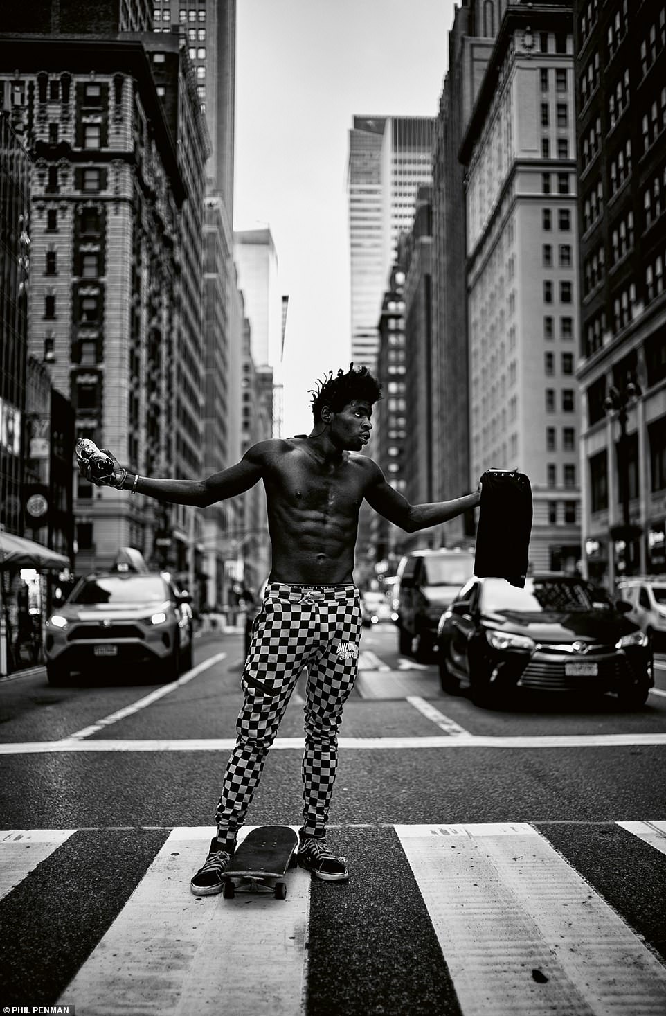 Ein Skateboarder auf der 5th Avenue trägt karierte Hosen, während er auf einem Fußgängerüberweg steht