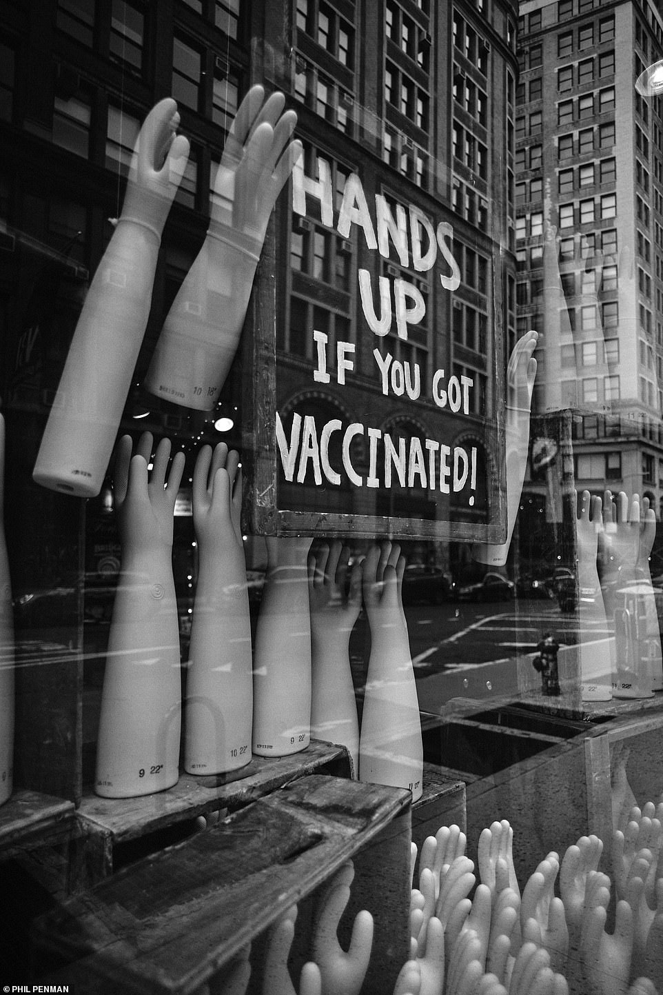 In einem Schaufenster am Broadway in New York City hängt ein Schild mit der Aufschrift: „Hände hoch, wenn Sie geimpft sind“