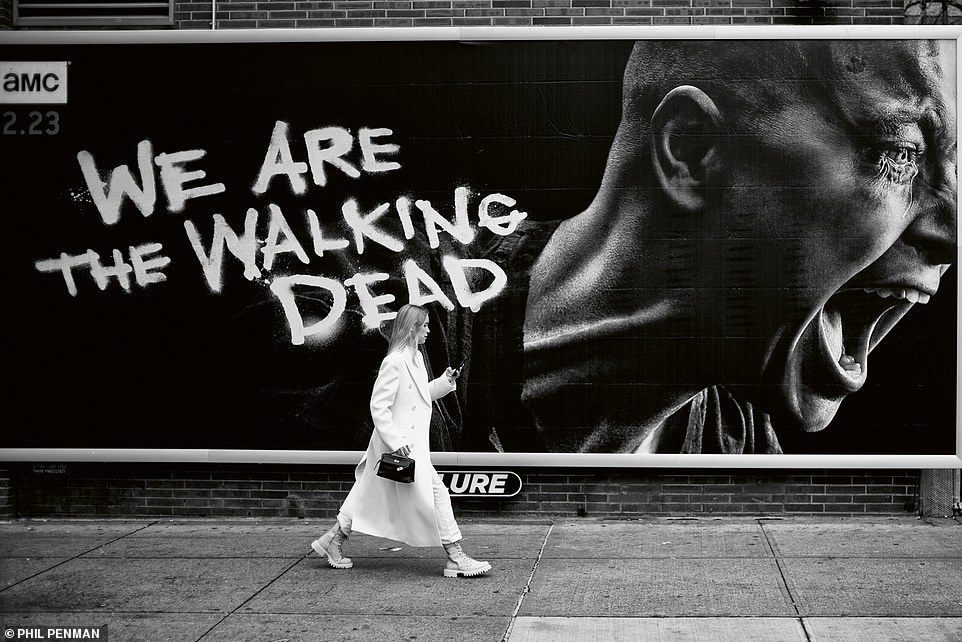 Eine modische junge Frau wird im Februar 2020 in Soho gesehen, wie sie an einem Plakat mit der Aufschrift „We Are The Walking Dead“ vorbeigeht