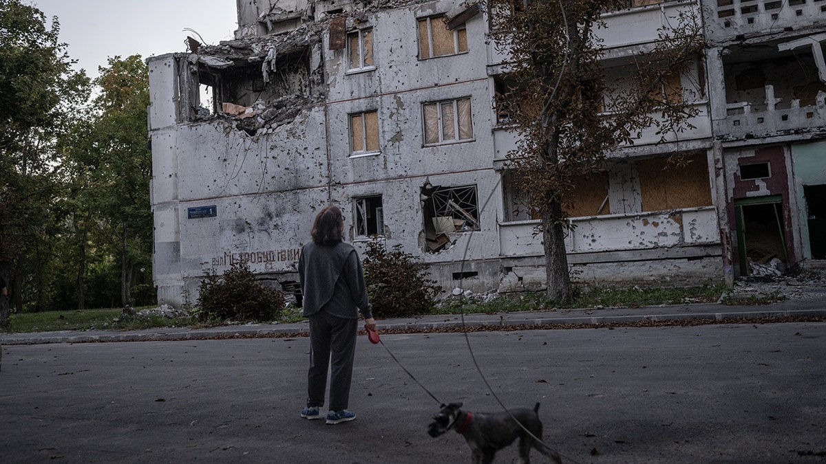 Eine Frau, abgerissenes Gebäude in der Ukraine