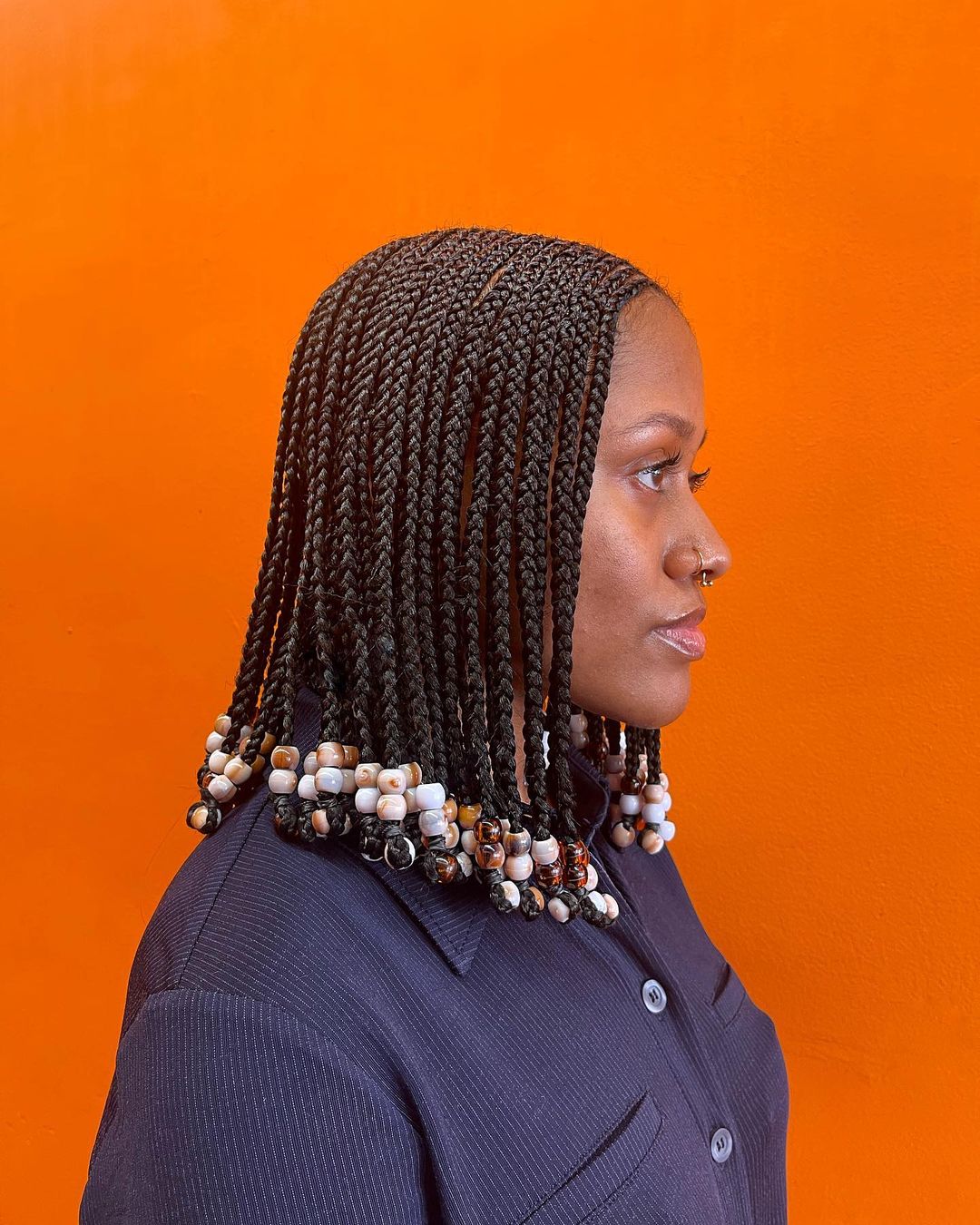 Schwarze Frau trägt kurze Box-Zöpfe mit Perlen
