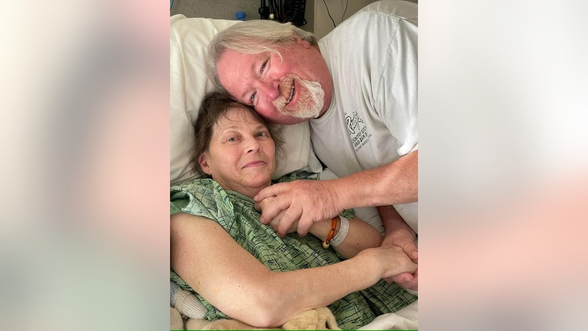 Dawn Lyn in einem grünen Krankenhauskittel mit ihrem Ehemann John Reese in einem weißen Hemd