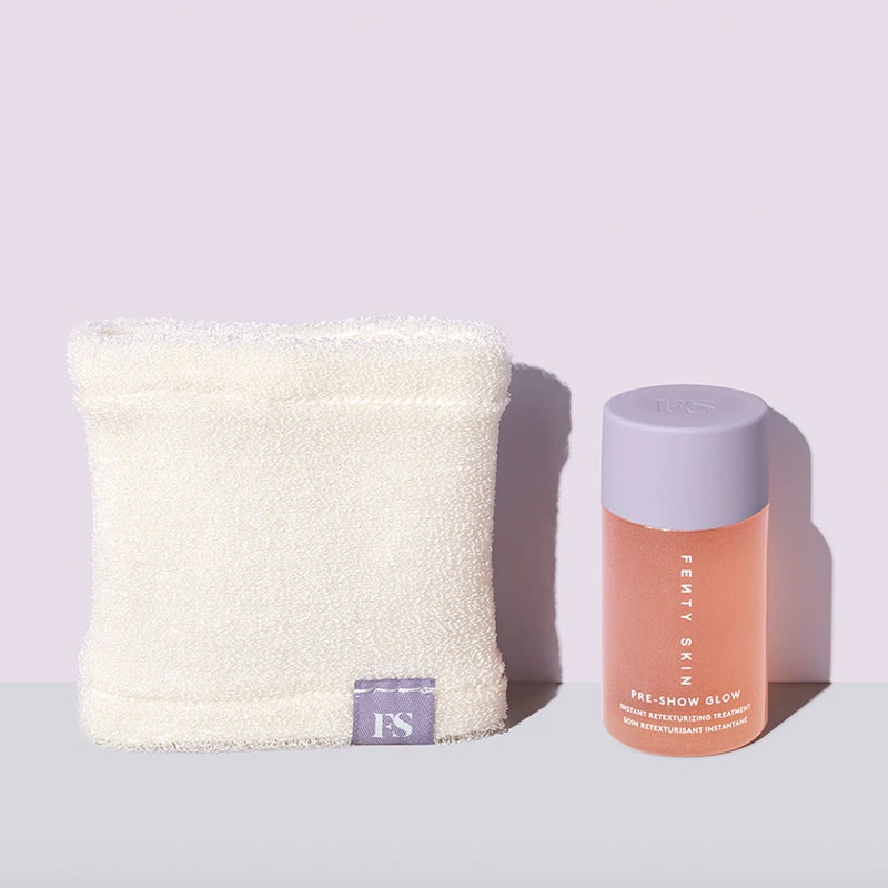 Eine kleine, durchsichtige, gefrostete Plastikflasche mit lavendelfarbenem Verschluss der Fenty Skin Pre-Show Glow Instant Retexturizing 10 % AHA-Behandlung mit weißem Applikatortuch auf violettem und grauem Hintergrund 