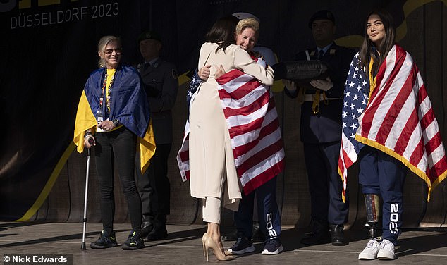 The athletes draped Meghan in the star spangled banner as they hugged her