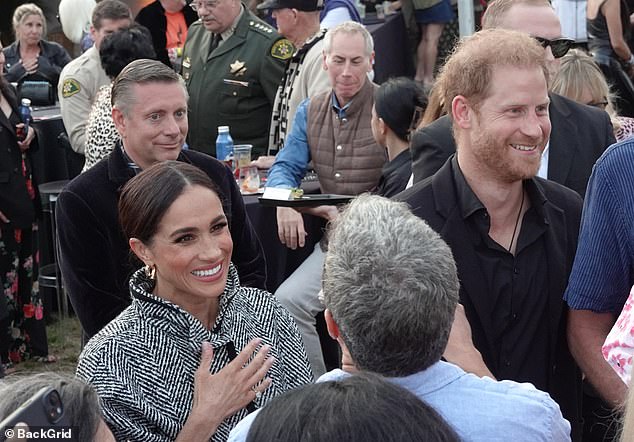 Meghan and Harry both sport big grins as they chat to the other VIP guests