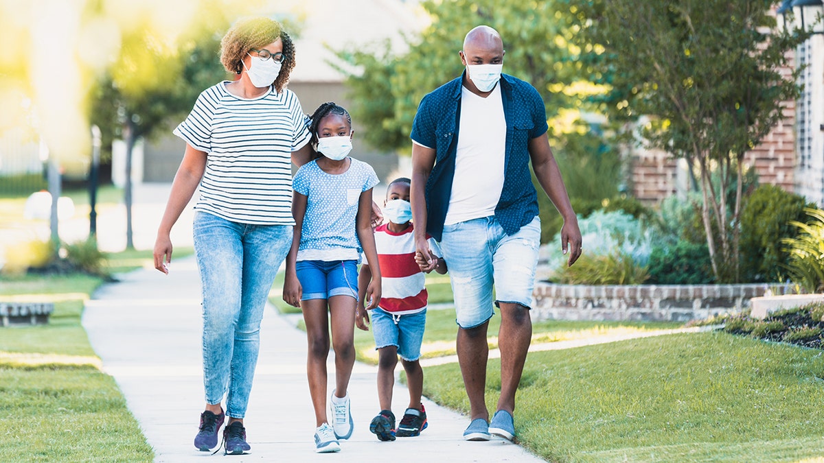 Familie trägt Masken beim Spaziergang