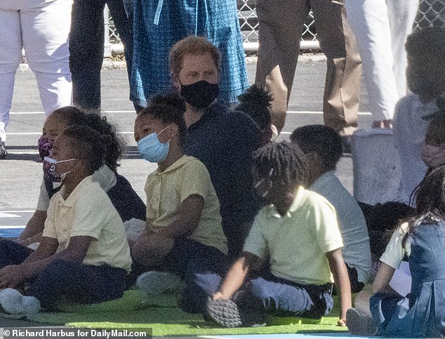 Prince Harry was snapped sitting among young school children who were given green cushions to sit on during Meghan's reading of her book