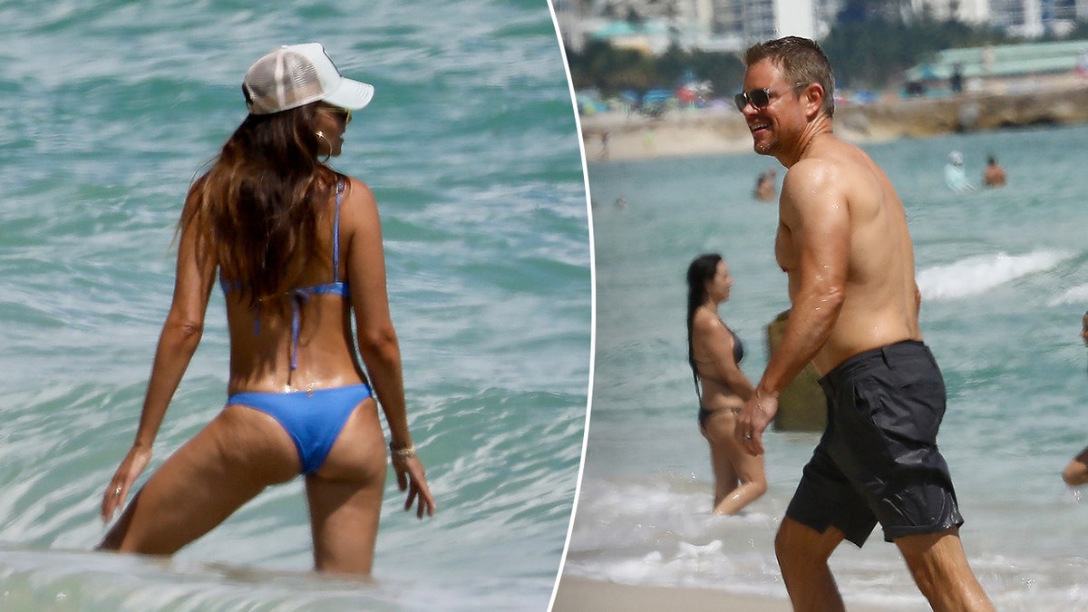 Luciana Barroso zeigt mit dem Rücken zur Kamera ihren Körper in einem blauen Split-Bikini. Matt Damon geht aus dem Wasser 