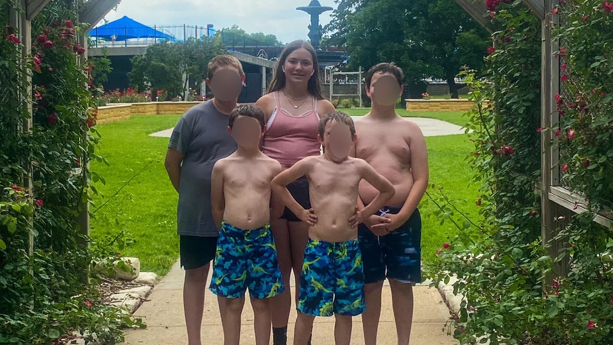 Teenie-Mädchen posiert mit ihren vier Brüdern draußen.