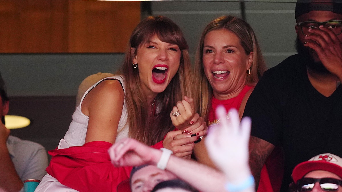Taylor Swift hält einen Freund in einer Suite beim Spiel der Kansas City Chiefs fest und lacht