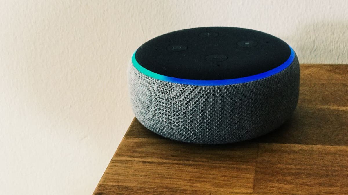 Ein graues Amazon Echo-Gerät auf einem dunklen Holztisch