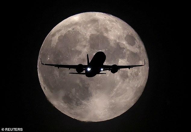 Ein Flugzeug fliegt gestern Abend vor dem Harvest-Supermond vorbei, als dieser seinen Landeanflug auf den Flughafen Heathrow in London macht