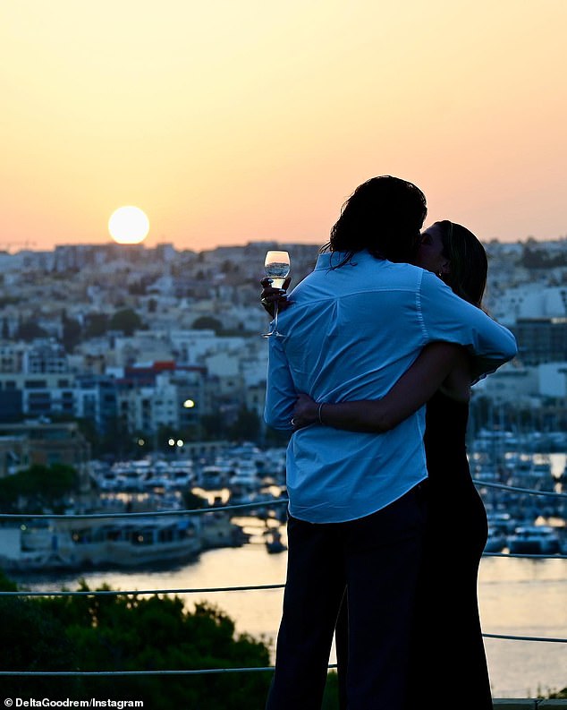 Die Sängerin teilte die Neuigkeit am Donnerstagabend auf Instagram mit, zusammen mit einem verliebten Foto des Paares im Urlaub auf Malta.  Auf dem Bild ist Delta zu sehen, wie sie Matthew zärtlich umarmt, vor einem atemberaubenden Blick auf das Meer, während die Sonne im Vordergrund untergeht