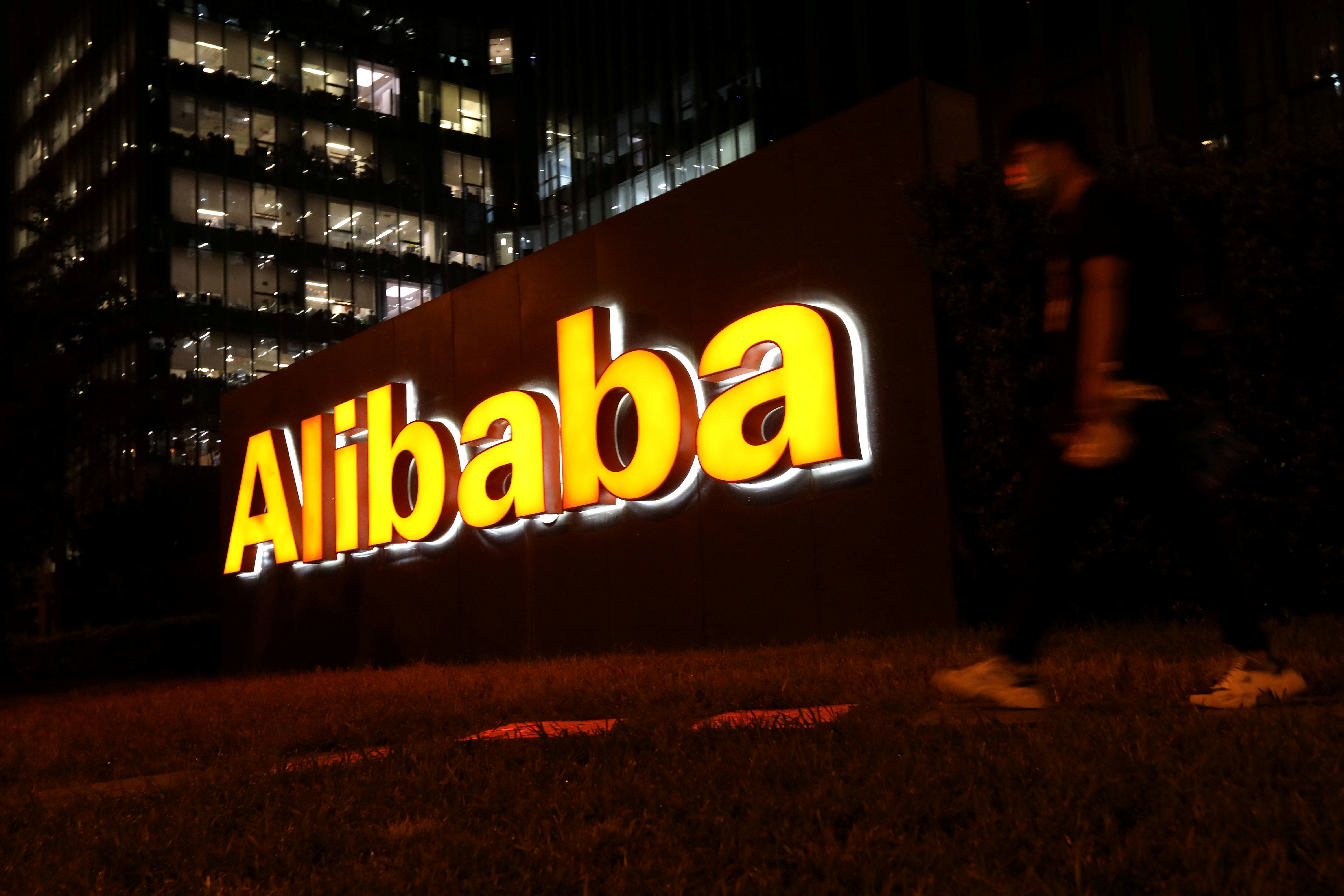 Mann geht an einem Logo der Alibaba Group in ihrem Bürogebäude in Peking vorbei