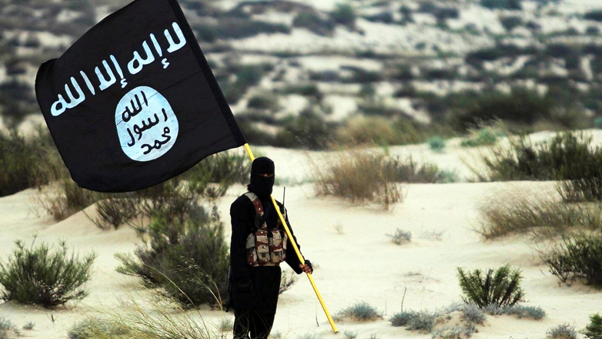 Ein Kämpfer des Islamischen Staates hält die ISIS-Flagge in einer Wüstenumgebung