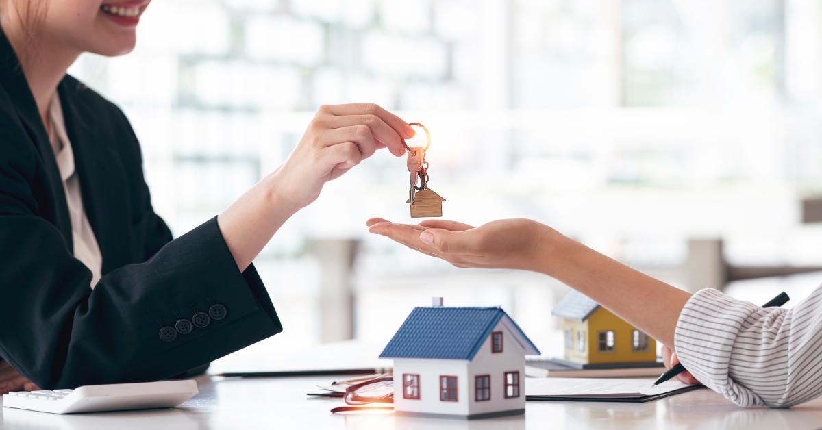 Ein Immobilienmakler übergibt seinem Kunden Hausschlüssel.