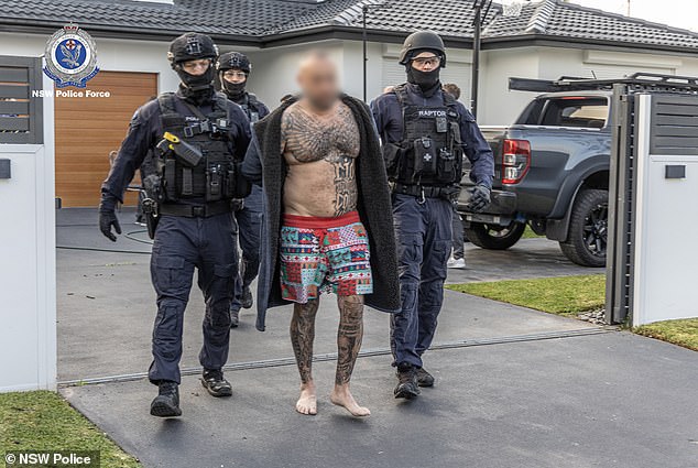 Der stark tätowierte Anführer der Outlaw-Motorradbande Lone Wolf, Medhat Mankaryous (Bildmitte), wurde am Freitag bei einer Razzia am frühen Morgen von Beamten der NSW-Polizei von seinem Grundstück vertrieben