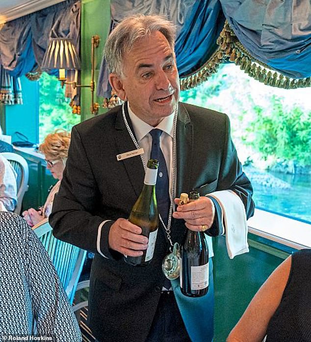 Auf dem Bild ist Mark als Weinkellner zu sehen, der Gäste an Bord des Kreuzfahrtschiffes Uniworld SS Catherine bedient