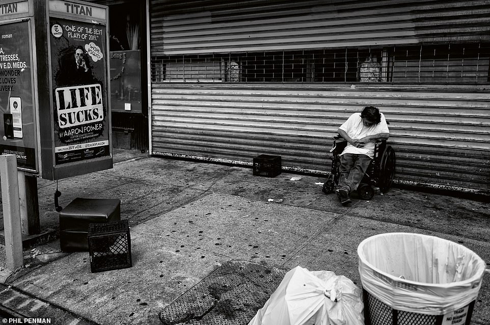 Ein Mann sackt in seinem Rollstuhl neben einem Plakat mit der Aufschrift „Das Leben ist scheiße“ zusammen.