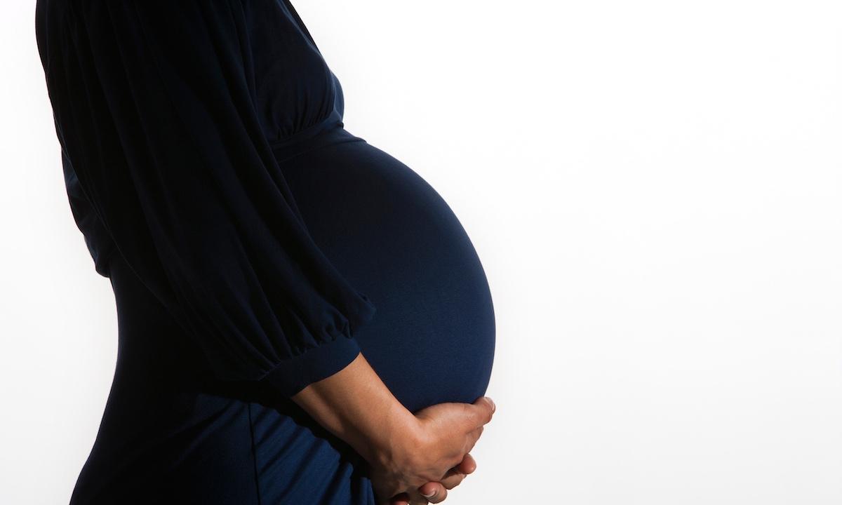 Eine schwangere Frau wiegt ihren Bauch.