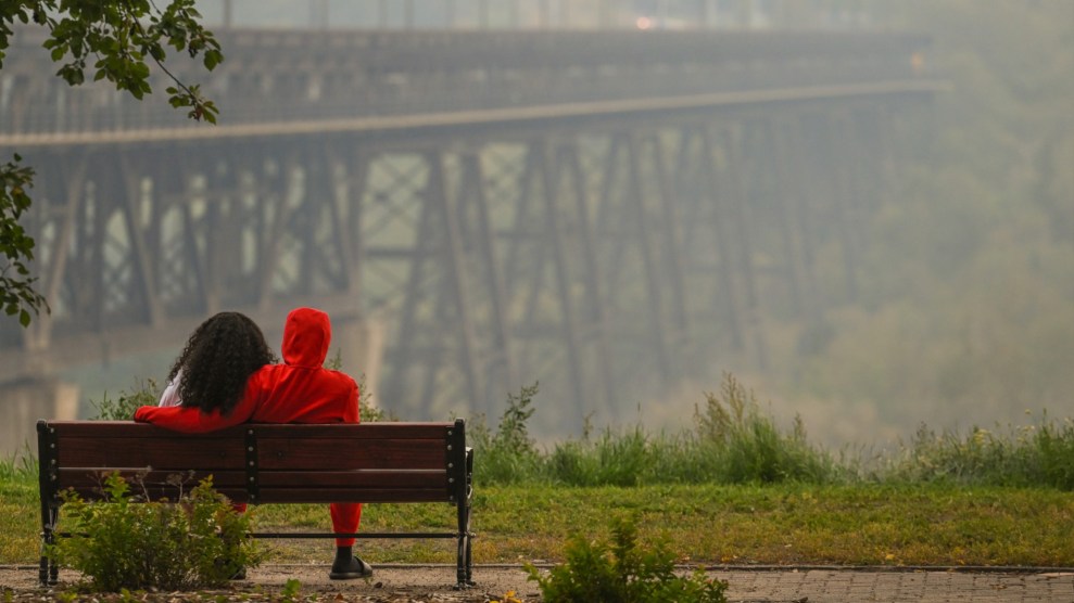 Ein Paar sitzt auf einer Parkbank und blickt auf eine dunstige Brücke.