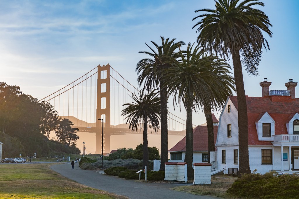 Häuser Palmen in der Nähe der Golden Gate Bridge bei Sonnenuntergang an einem warmen Sommerabend