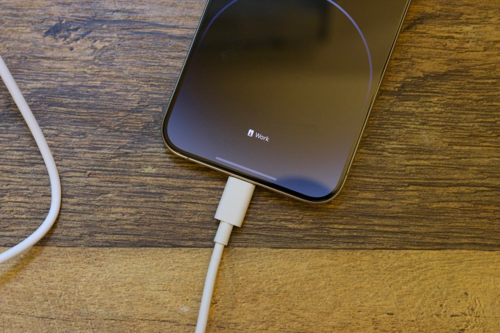 An iPhone 15 Pro Max charging with a USB-C cable.