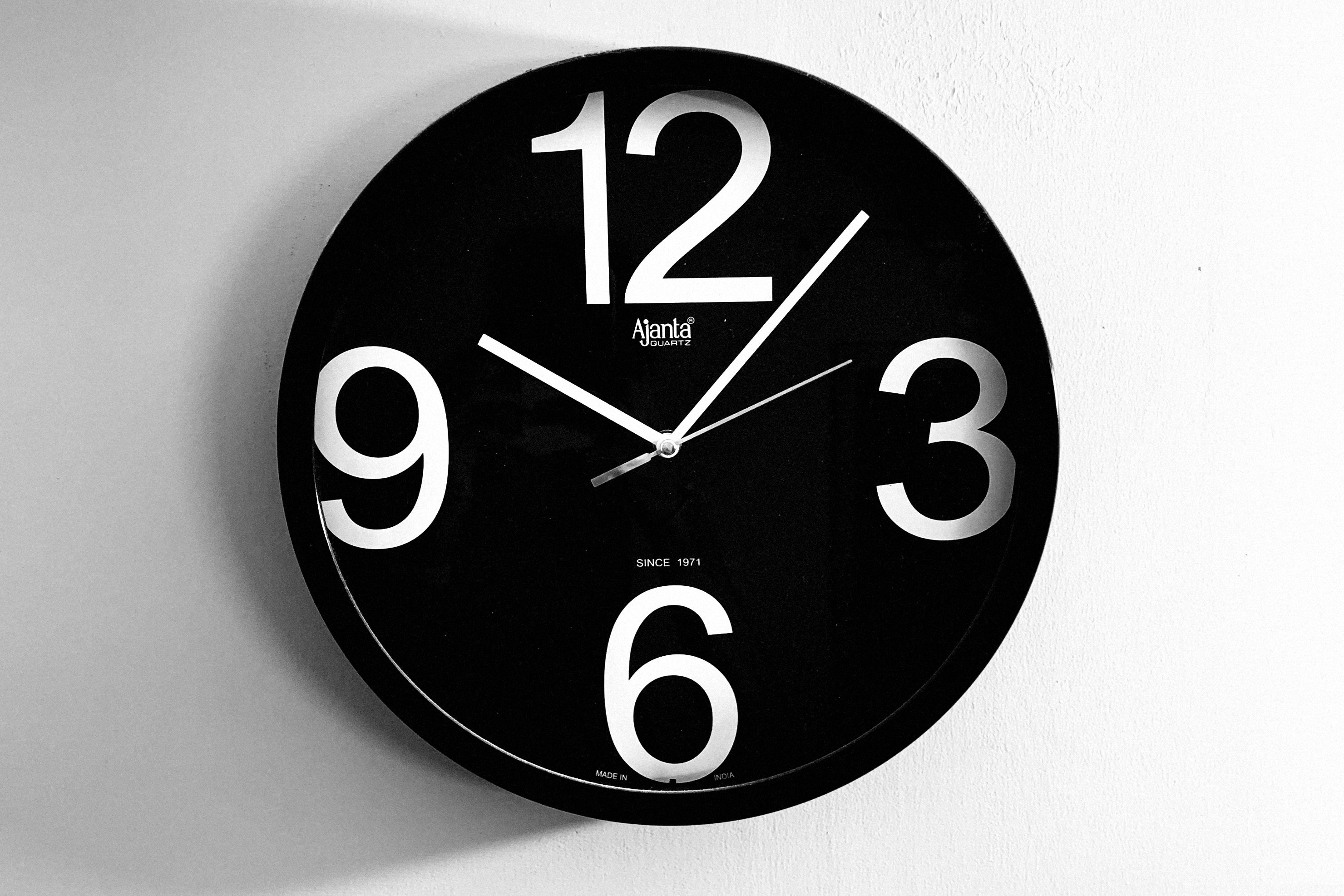 Eine schwarze Uhr mit weißen Zahlen und Zeigern, die 10:05 zeigen.