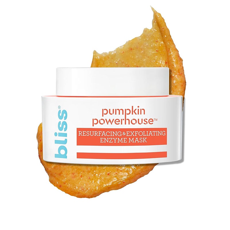 Bliss Pumpkin Powerhouse-Gesichtsmaske: Ein orangefarbenes Gesichtsmaskenmuster hinter einem weiß-orangefarbenen Glas auf weißem Hintergrund
