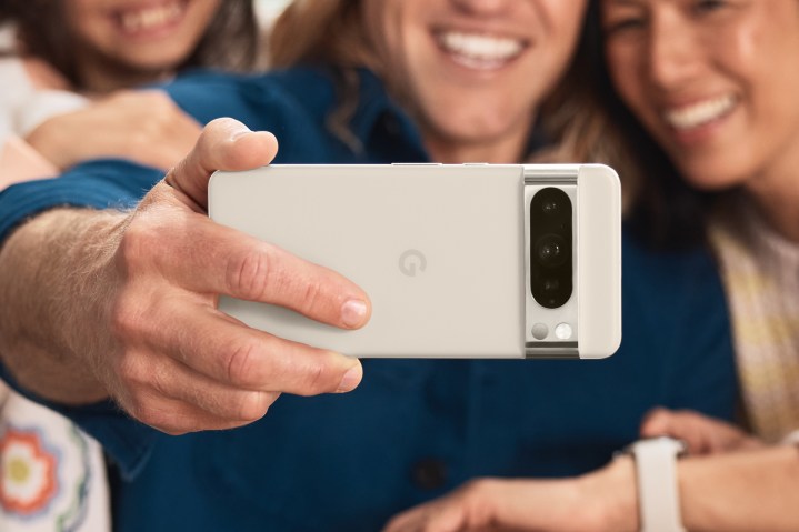 Jemand hält ein weißes Google Pixel 8 Pro in der Hand, um ein Gruppen-Selfie zu machen.