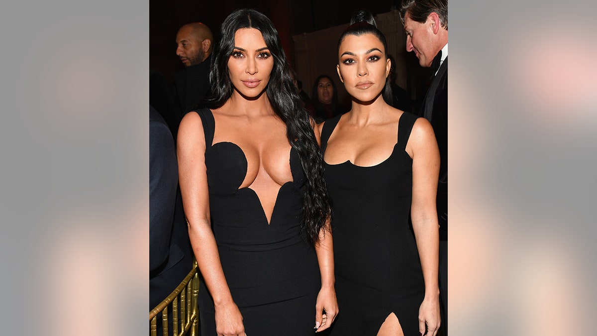 Kim Kardashian posiert in einem sehr tiefen schwarzen Kleid für ein Foto mit Schwester Kourtney Kardashian in einem schwarzen Kleid bei der amfAR-Gala