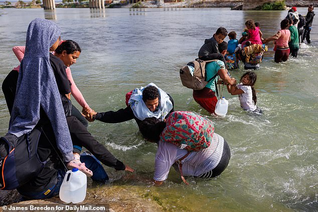 Migranten, hauptsächlich aus Venezuela, warten am Ufer der US-Seite des Flusses, bis die Grenzpolizei am 27. September eintrifft, um den von der texanischen Nationalgarde installierten Stacheldraht aufzuschneiden