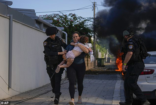 Israelische Polizisten evakuieren am Samstag eine Frau und ein Kind von einem Ort, der von einer aus dem Gazastreifen abgefeuerten Rakete in Aschkelon im Süden Israels getroffen wurde