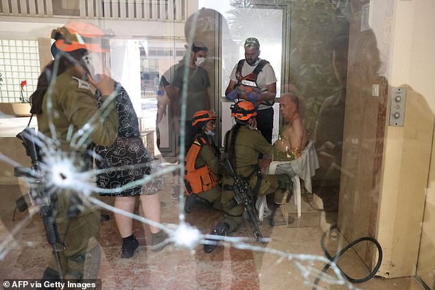 Israelische Rettungsteams kümmern sich um einen älteren Mann, der auf einem Stuhl im Eingang eines Gebäudes sitzt, das in Aschkelon während eines Raketenangriffs aus dem Gazastreifen direkt getroffen wurde