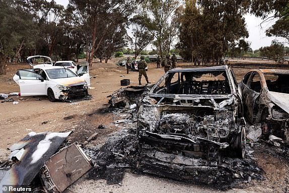 Israeli soldiers inspect burnt cars that are abandoned in a carpark near where a festival was held before an attack by Hamas gunmen from Gaza that left at least 260 people dead, by Israel's border with Gaza in southern Israel, October 10, 2023. REUTERS/Ronen Zvulun