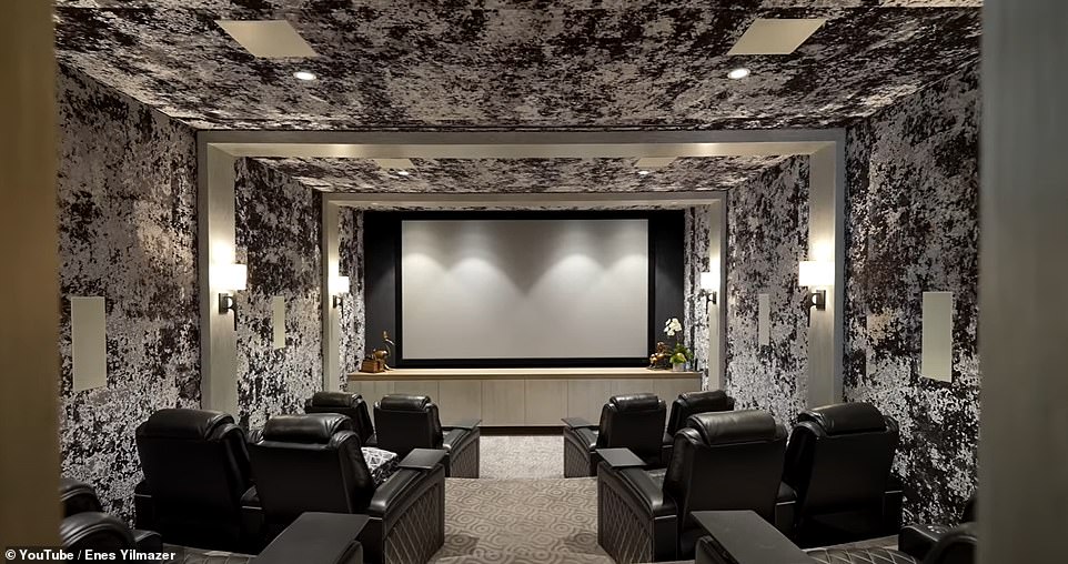 Das Kino auf der unteren Ebene verfügt über drei Sitzreihen, Ledersessel, eine riesige Leinwand, einen Projektor dahinter und eingebaute Lautsprecher. [and] gepolsterte Wände