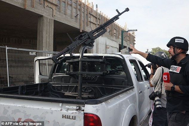 Journalists take pictures of a pickup truck mounted with machine gun in the southern city of Sderot on October 7