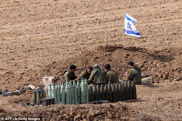 Israeli soldiers take a break as they hold a position along the Israel-Gaza border on October 11, 2023