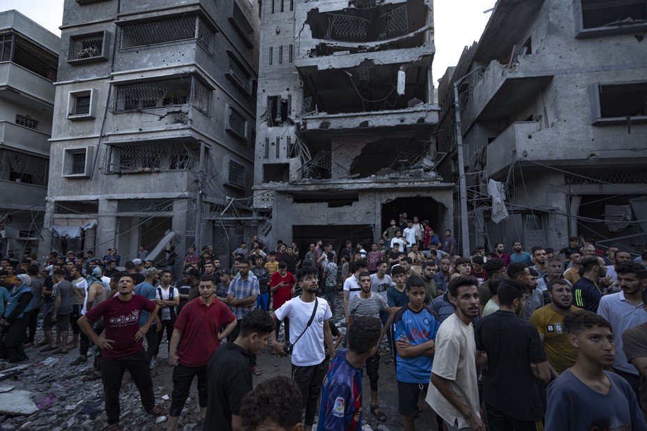 Bild von Palästinensern, die anderen zuschauen, wie sie in den Trümmern eines zerstörten Wohngebäudes nach einem israelischen Luftangriff suchen, Dienstag, 10. Oktober 2023.