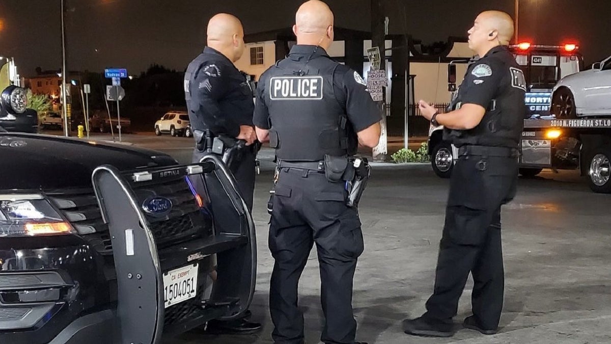 Drei uniformierte LAPD-Beamte stehen in der Nähe eines Abschleppwagens