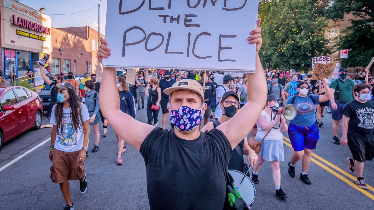 Ein Demonstrant in New York hält eine "der Polizei die Mittel entziehen" Zeichen