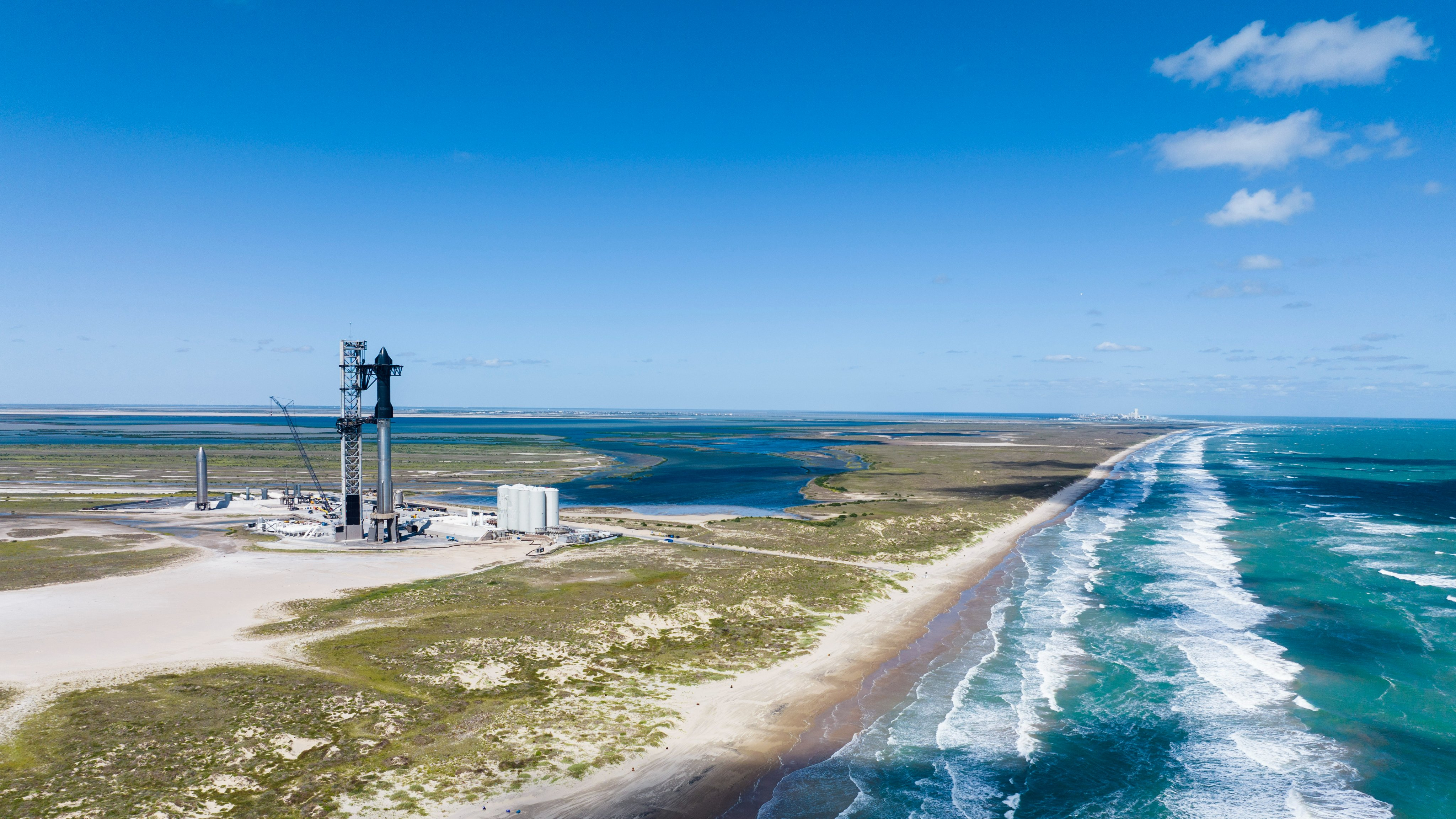 Die Edelstahl-Raumschiffrakete von SpaceX steht auf ihrer Startrampe, in der Nähe das türkisfarbene Wasser des Golfs von Mexiko.
