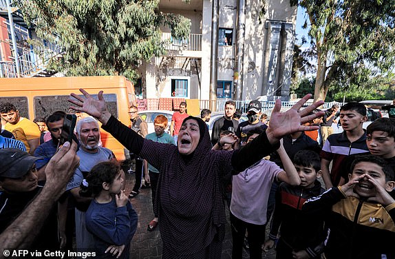 TOPSHOT - A woman reacts as people gather at the site of the Ahli Arab hospital in central Gaza on October 18, 2023 in the aftermath of an overnight strike there. A blast ripped through a hospital in war-torn Gaza killing hundreds of people late on October 17, sparking global condemnation and angry protests around the Muslim world. Israel and Palestinians traded blame for the incident, which an "outraged and deeply saddened" US President Joe Biden denounced while en route to the Middle East. (Photo by AFP) (Photo by -/AFP via Getty Images)